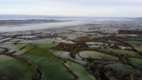 aerial reverse shot of a devon countryside valley in england with river mist and frost