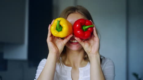 chica sonriente cubriendo sus ojos con pimientos de pimentón