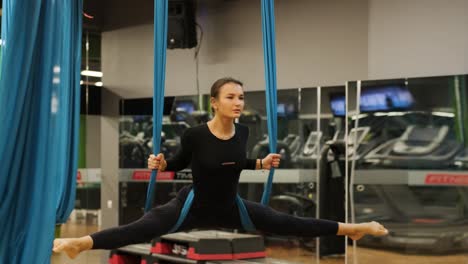 mujer atractiva haciendo ejercicios de estiramiento de aero yoga en hamacas en un estudio de fitness. estilo de vida saludable para mujeres. gimnasio de entrenamiento