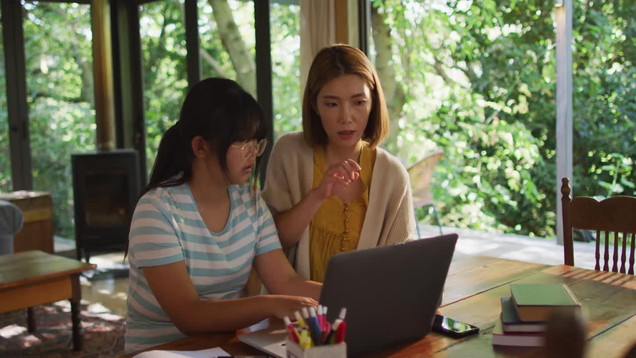 아시아 어머니와 딸이 함께 배우고 노트북을 사용합니다.