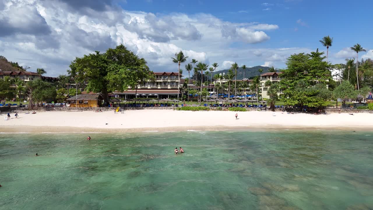 드론 영상은 은 바물, 나무, 그리고 럭셔리 빌라를 가진 조용한 푸켓 해변을 밝은 낮빛 아래서 포착합니다.
