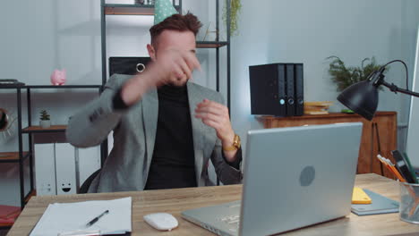 Happy business man dancing victory dance celebrating start of weekends holiday success win in office