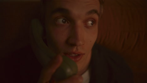 close-up of young man resting on sofa, talking on retro-style phone