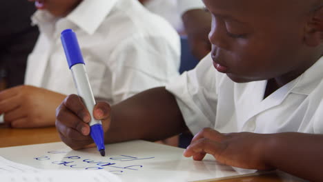 niño de escuela primaria escribiendo en su escritorio, de cerca