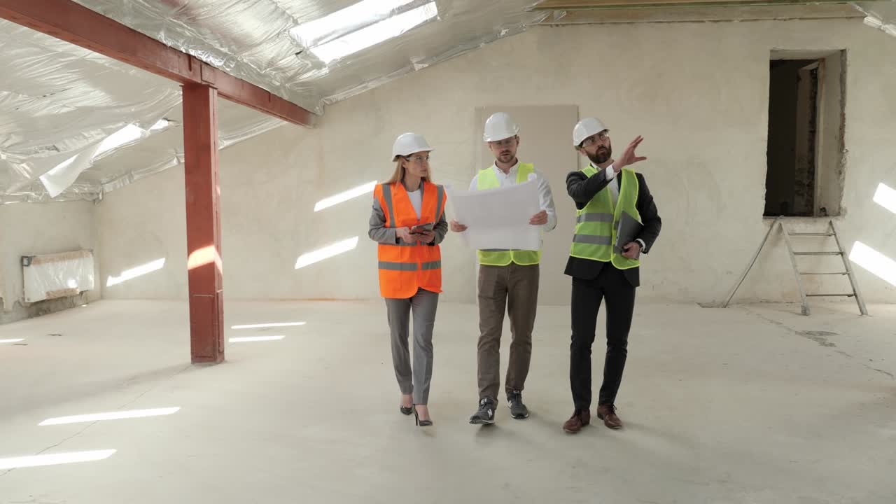 Group of three people two businessman investor and architect engineer analyzing and discuss the plan of construction site they wearing a safety helmets. Investor and Worker Finish Industrial Building.