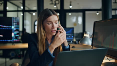 annoyed businesswoman talking smartphone at workplace. nervous stock trader work