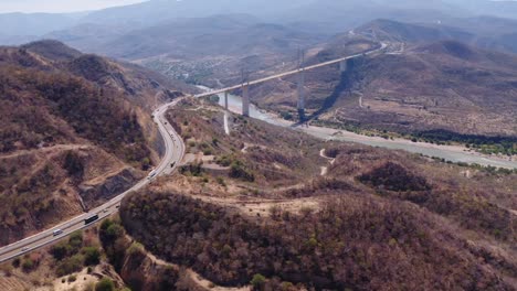 Epic-aerial-daytime-slow-tilt-up-drone-shot-of-Puente-Mezcala-in-Guerrero-Mexico,-on-the-Autopista-del-Sol-highway-between-CDMX-and-Acapulco