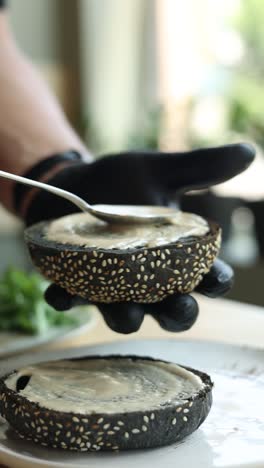 chef preparing a gourmet burger with black sesame bun