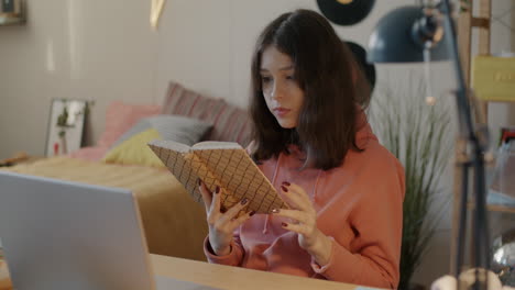 teenage girl reading a book at her desk