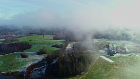 vista aérea de la niebla moviéndose sobre una granja rural remota, restos de nieve en el paisaje boscoso