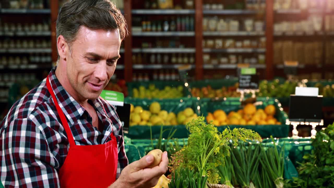 Empleado sonriente revisando verduras en la sección de productos orgánicos