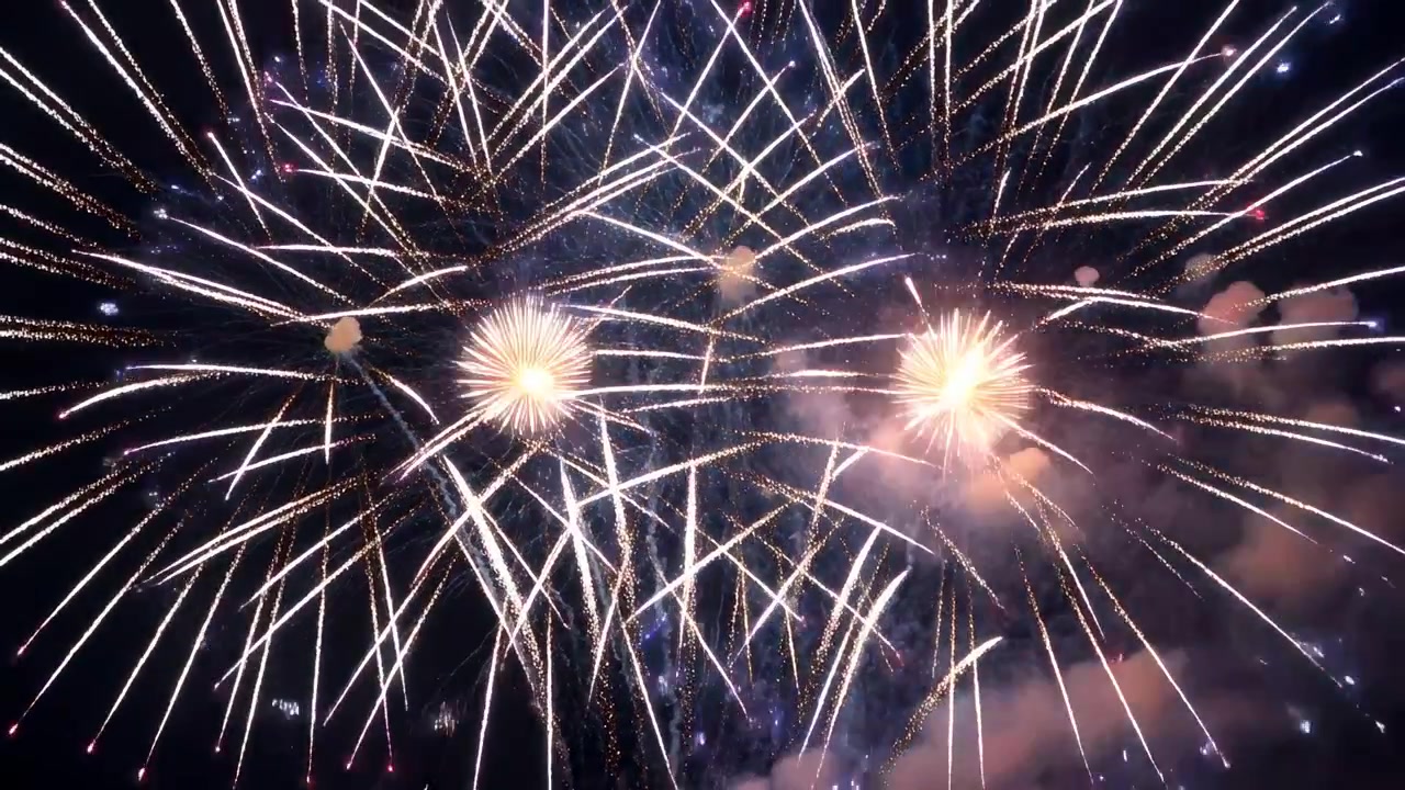 Fuochi d'artificio aerei che si accendono e si lanciano nel cielo notturno per uno spettacolo pubblico, formando esplosioni a crisantemo