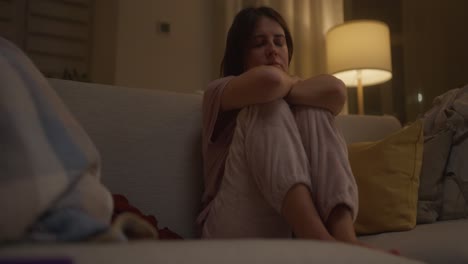mujer sentada sola en un sofá por la noche