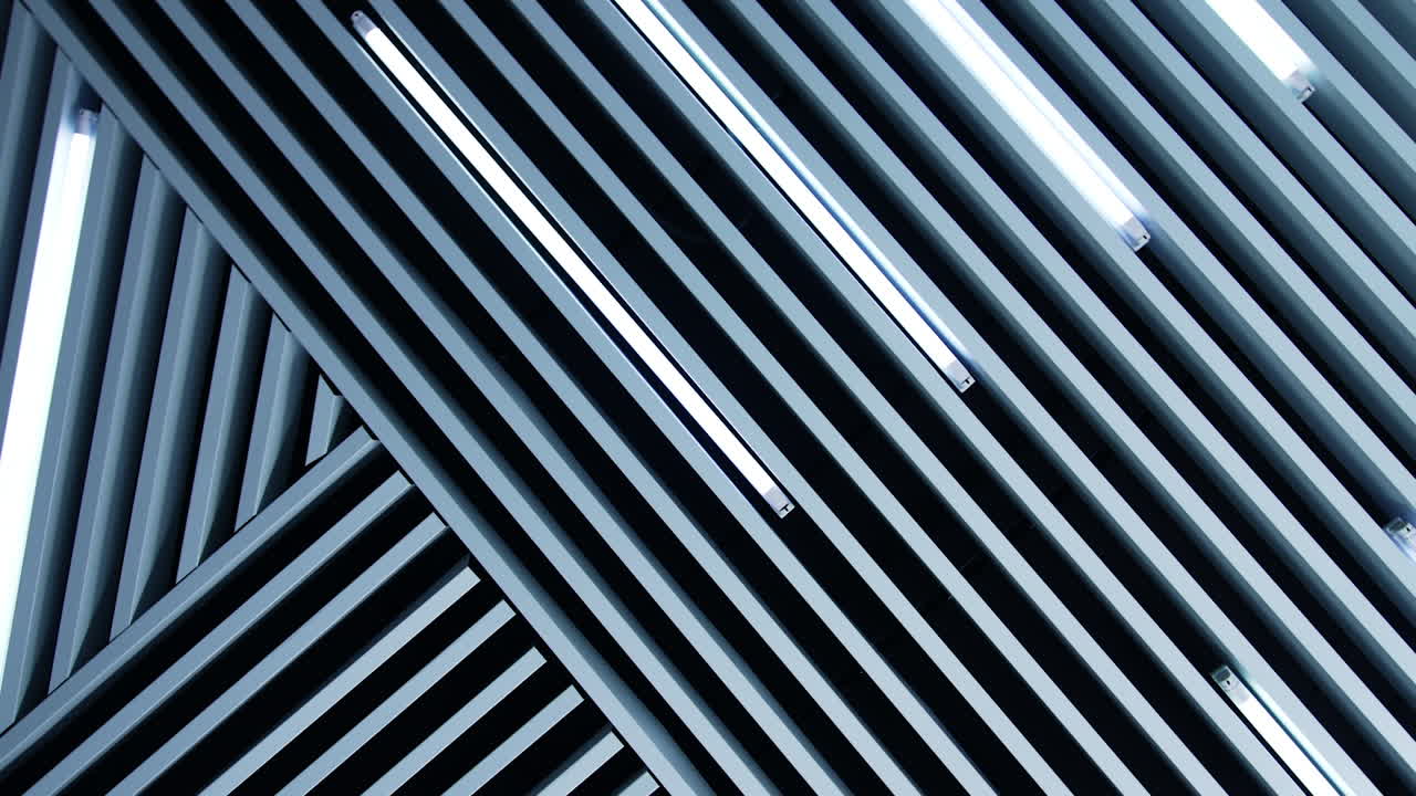 Unusual design of the ceiling in the room. Decorative planks with lamps of daylight among them. Low angle view.