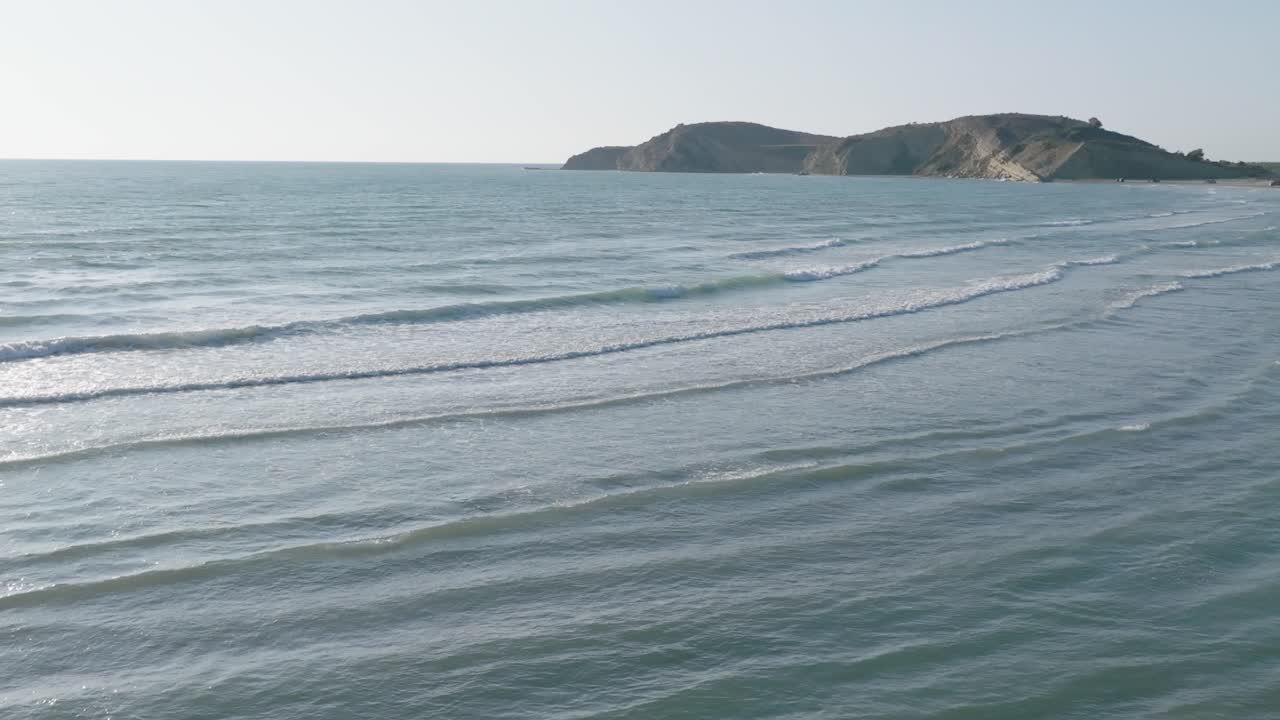 海面波浪慢動作，遠處可見山丘及岩石海岸。