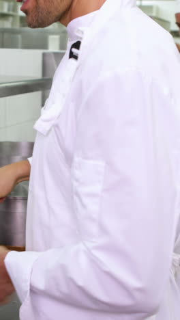 smiling chef frying vegetables in a wok and adding oil