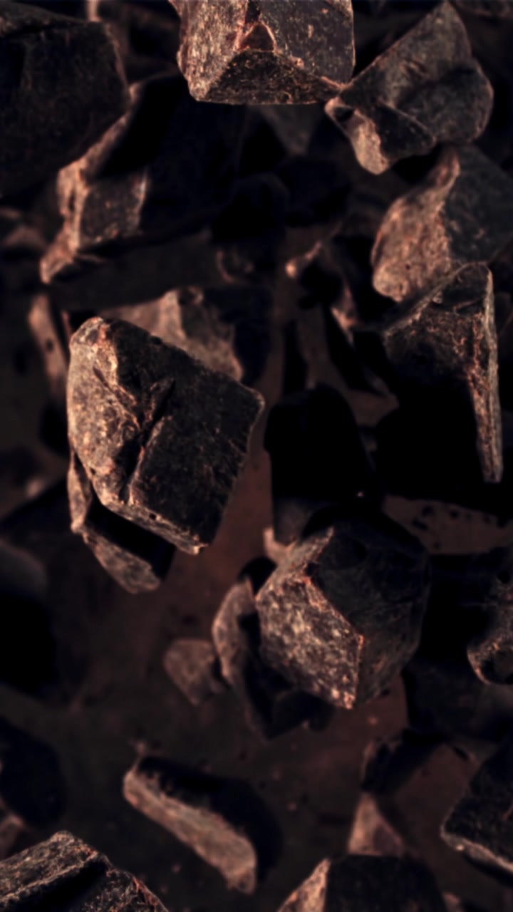 Cámara lenta de cacao en polvo cayendo sobre trozos de chocolate negro