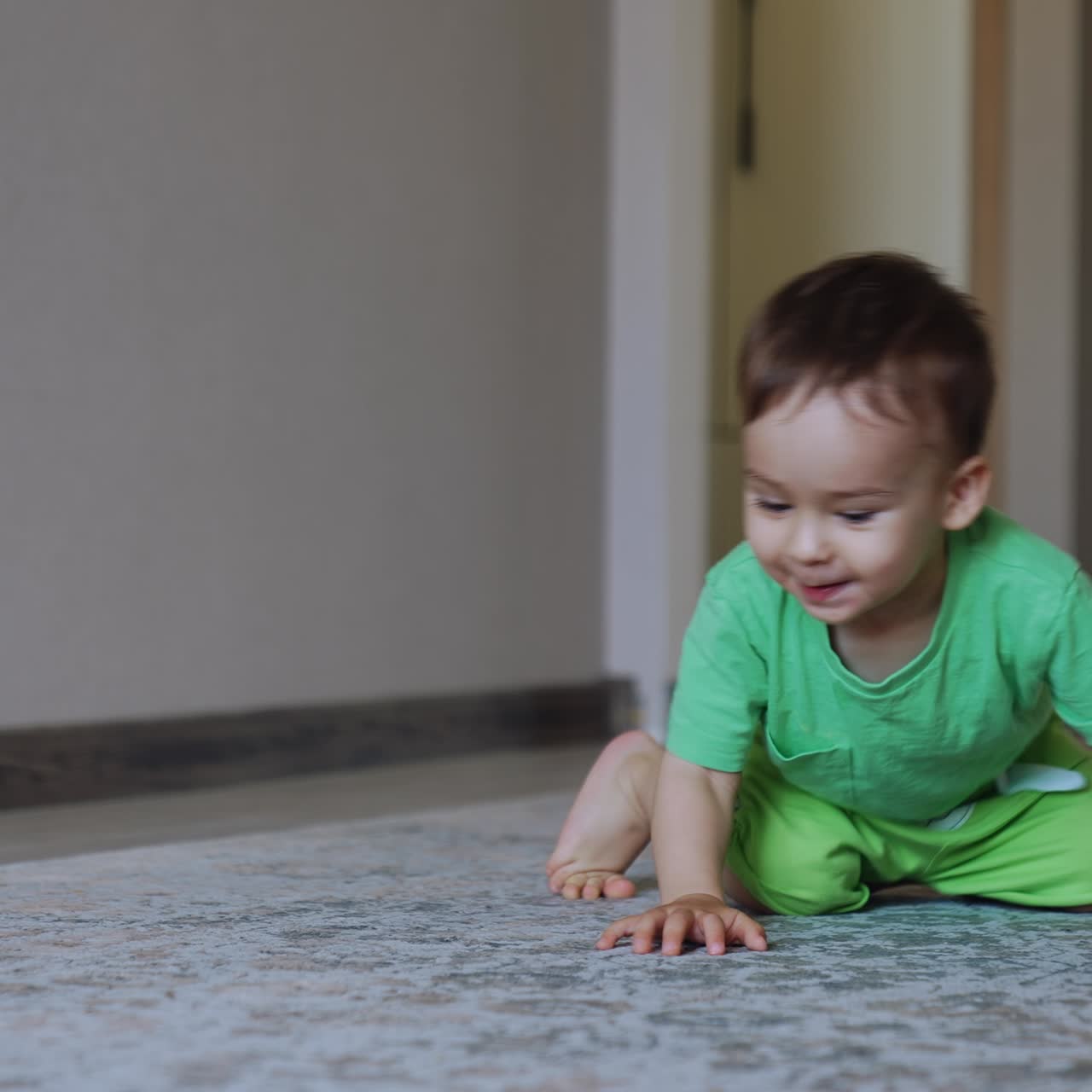Healthy Caucasian baby boy playing with a train. Toy vehicle goes away and kid cheerfully follows it