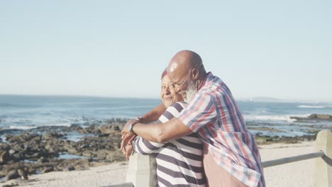 Happy-senior-african-american-couple-embracing-on-promenade-by-the-sea,-slow-motion