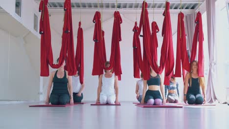 young women team stretches at hard aerial fly yoga class