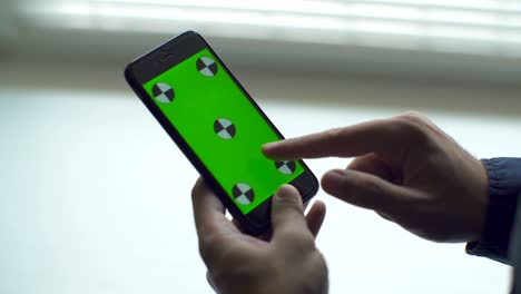 hombre sosteniendo una pantalla táctil de teléfono inteligente con pantalla verde clave de croma para contenido personalizado