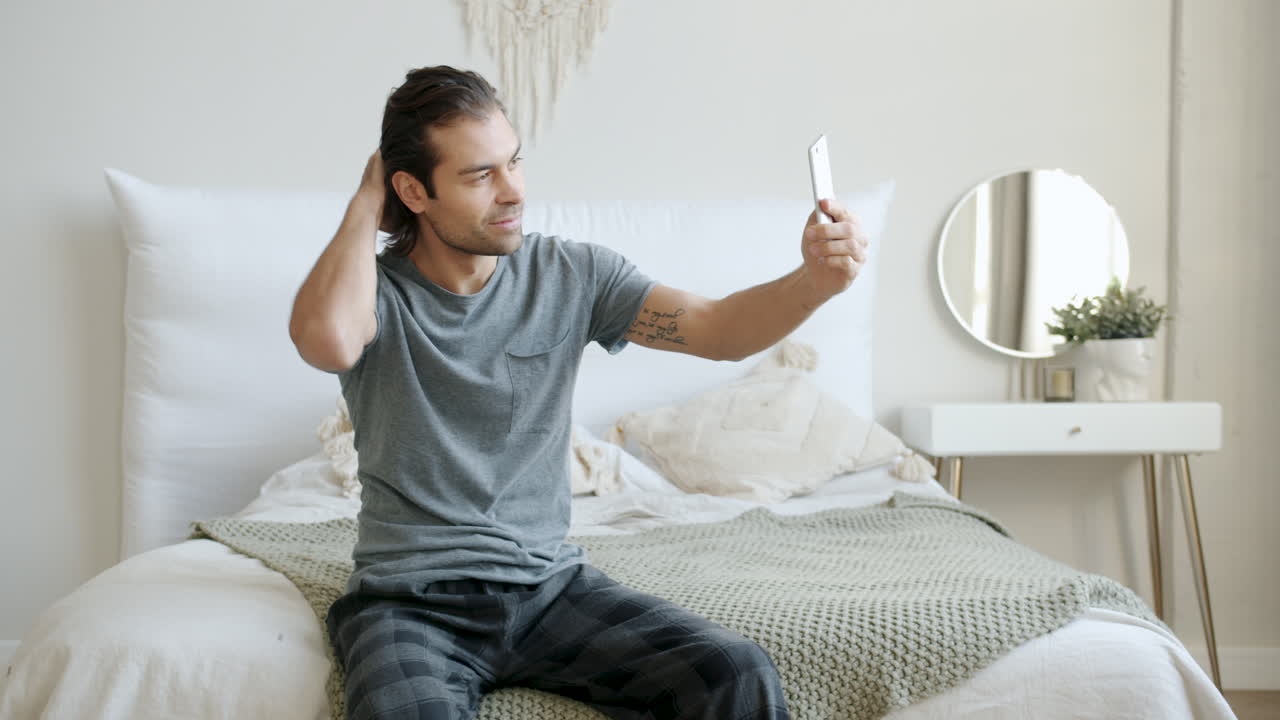 Uomo che si fa un selfie in camera da letto