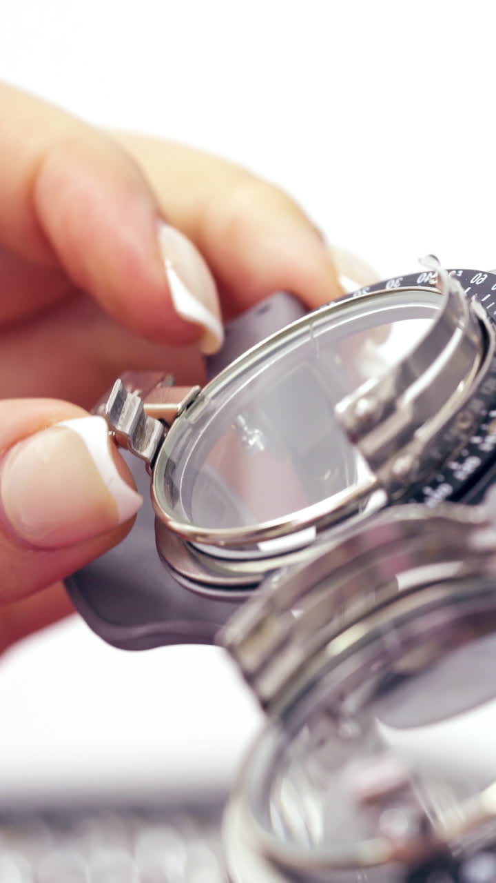Woman's hand taking lens for putting it into testing glasses. Image of an optometry set. Lens set for the selection of points. Close-up. Vertical video
