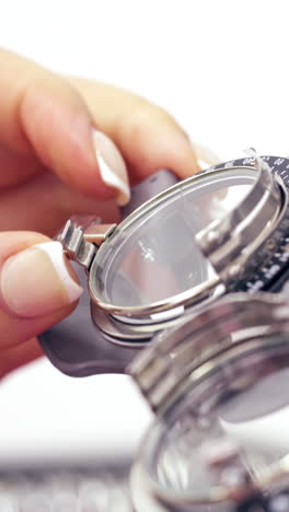 woman's hand taking lens for putting it into testing glasses. image of an optometry set. lens set for the selection of points. close-up. vertical video