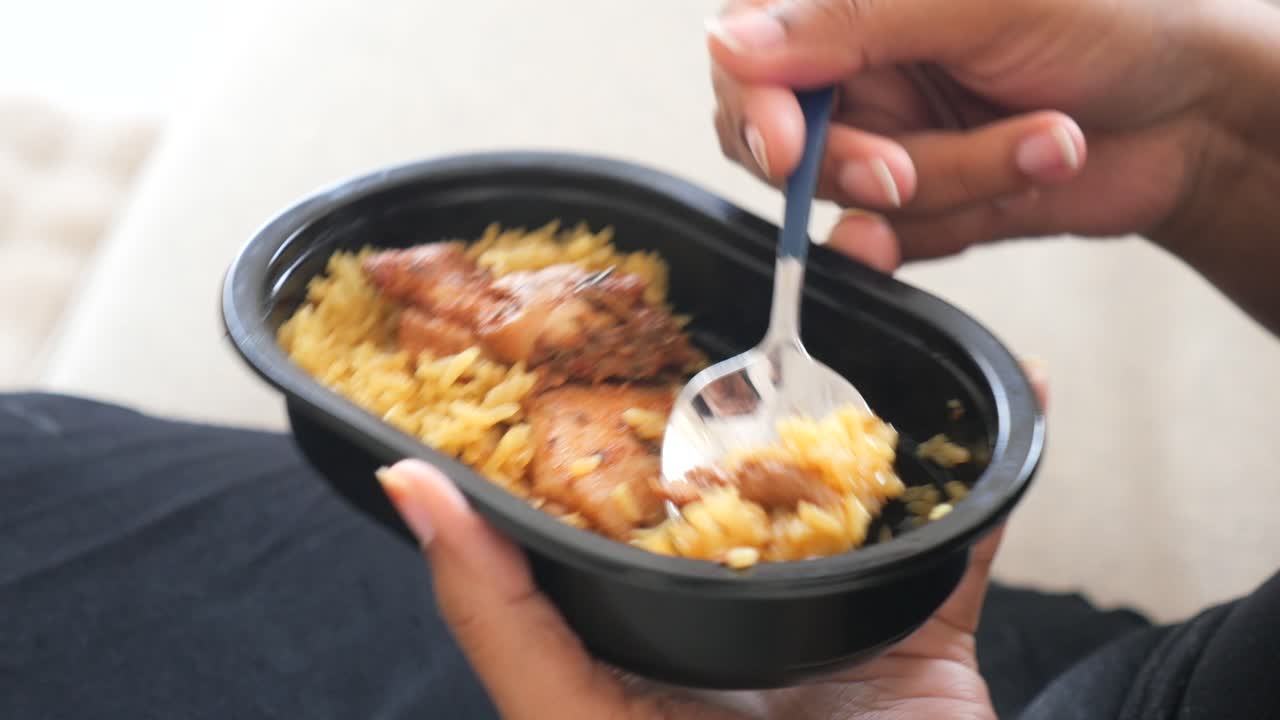 A person is eating chicken and rice from a bowl