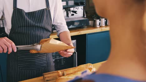 Mid-section-of-waitress-packing-croissants-in-paper-bag