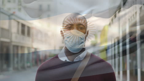 animation of flag of argentina waving over man wearing face mask during covid 19 pandemic