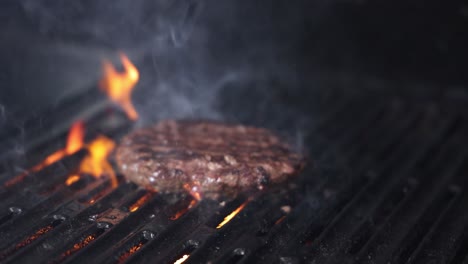 burger patty cooking with flames on grill