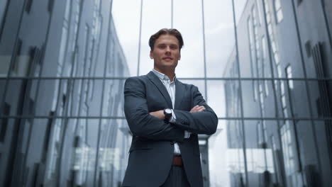 portrait smiling businessman standing outside glass office building alone