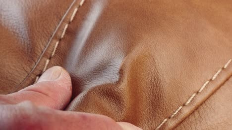 hand stretches leather to expose small tear on furniture surface clearly