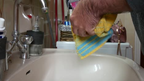 man in quarantine wiping his wet hands with a towel after washing