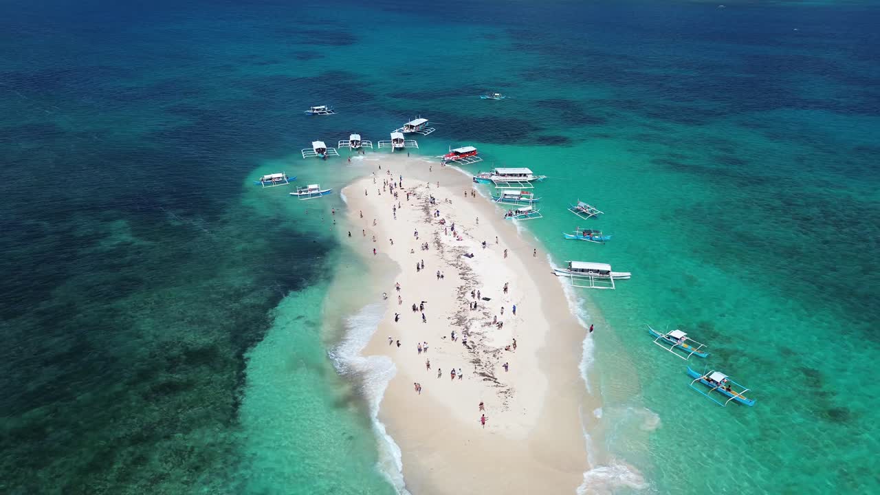 Aerial profile shot of bare island in Siargao with tourists from docked boats