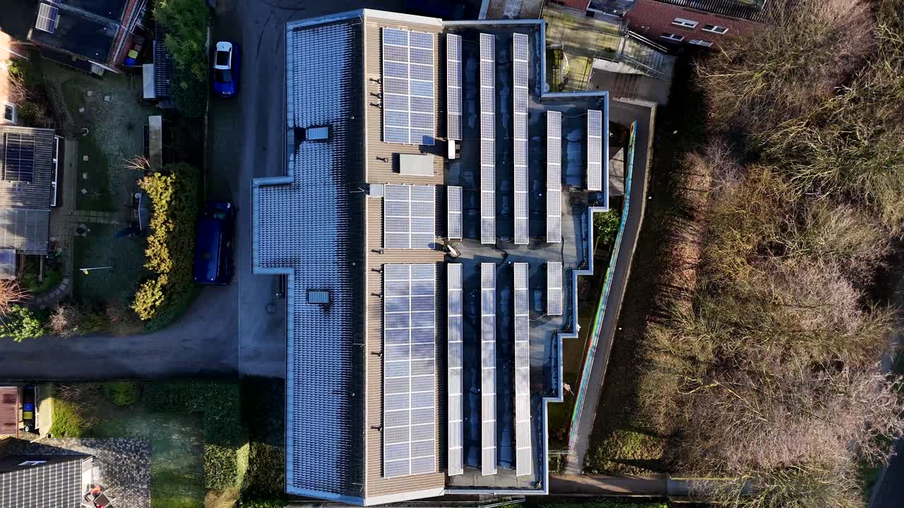 Modern solar panels on roof of residential Apartment during sunrise in the morning. Frosty and icy winter day in american suburb. Aerial top down flyover shot.