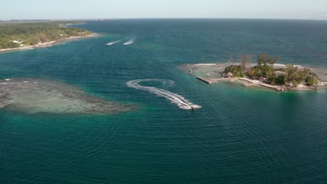 speed boat drives quickly across channel outside of utila honduras, aerial overview