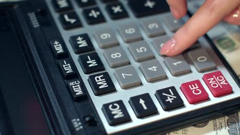 business woman hand using calculator at office. calculator on dollar banknotes