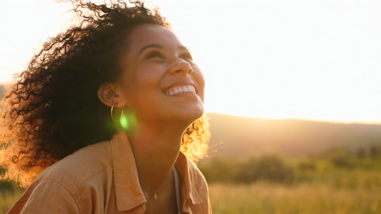 Um vídeo em close-up captura uma mulher alegre sorrindo em um campo ensolarado, com um brilho quente e dourado.