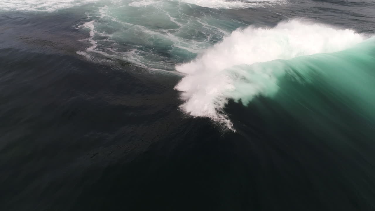 Wave folds and glows in backlight, slow motion reveals smooth surface detail and ripple