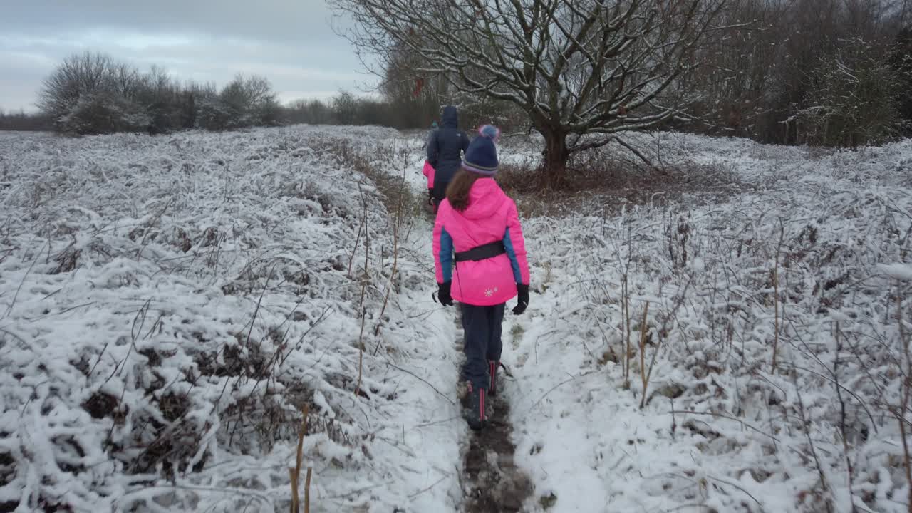 Family walking on path track in snow field
