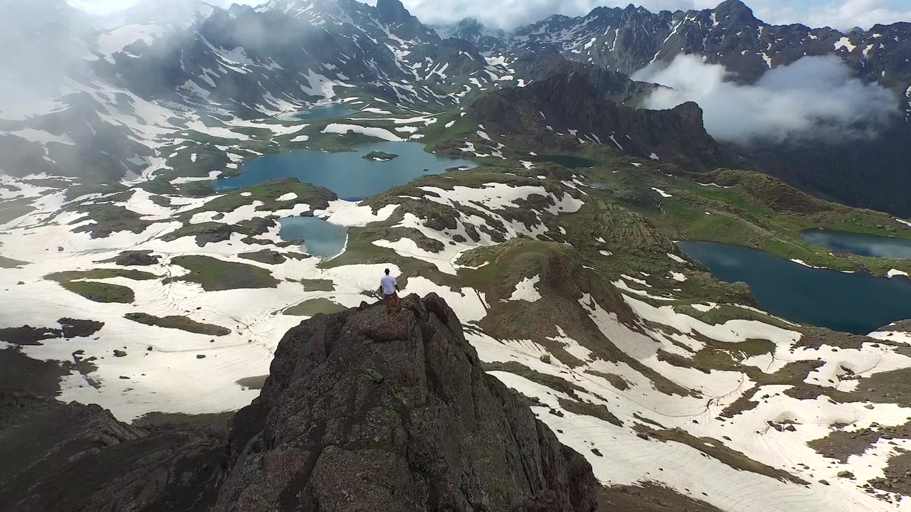 Hiker Standing on Mountain Peak Overlooking Alpine Lakes