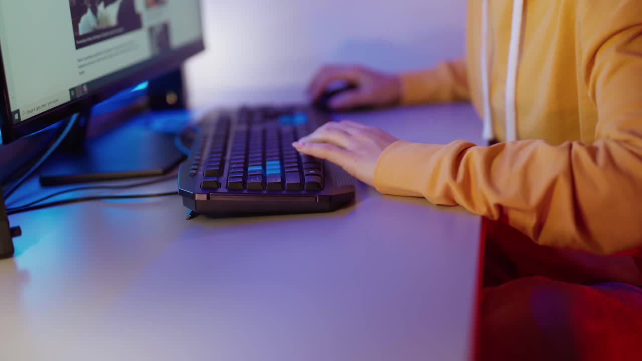 Woman's hands press the buttons on the keyboard. Girl is sitting at the table and and working on the computer. Close-up.