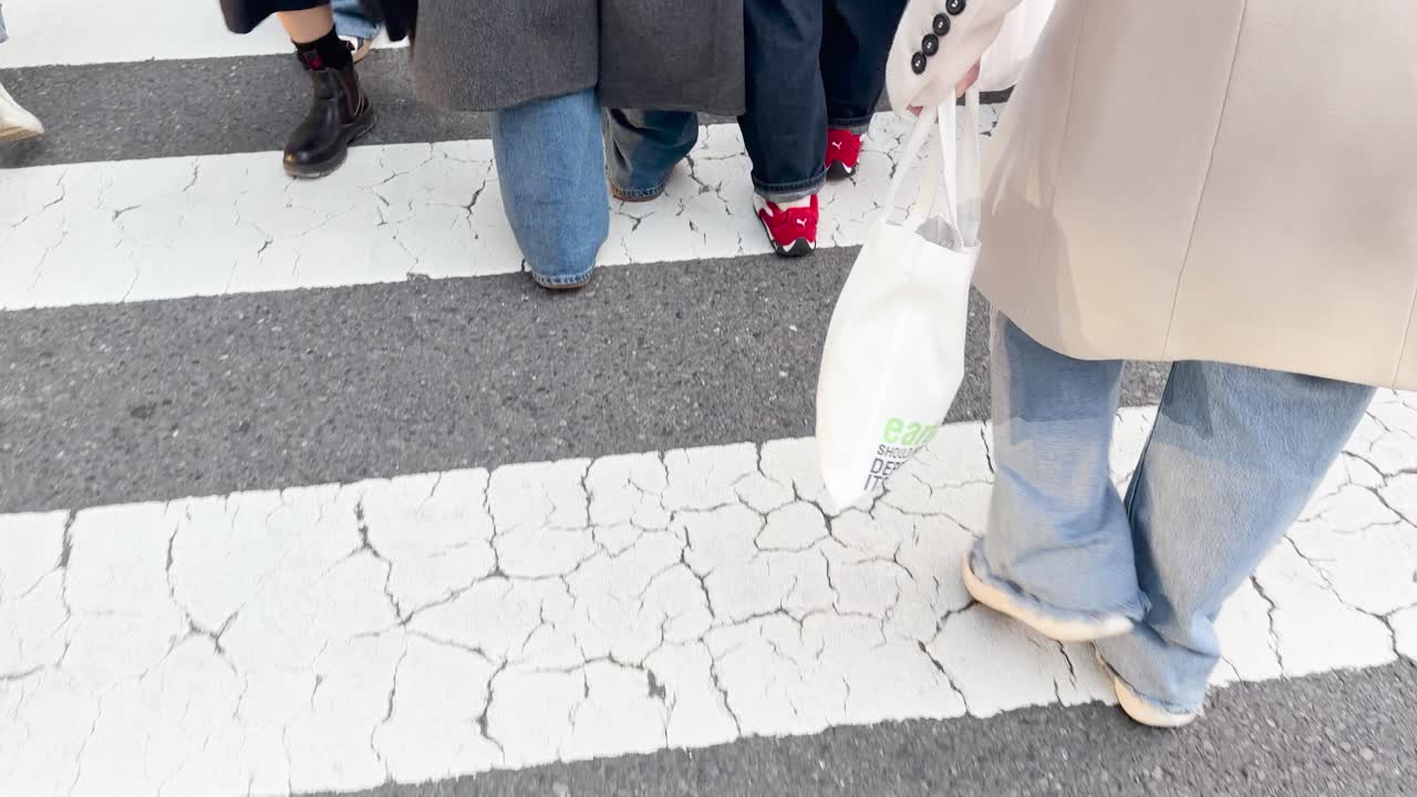 街中の白い縞模様の横断歩道を人々が渡るローアングルショット