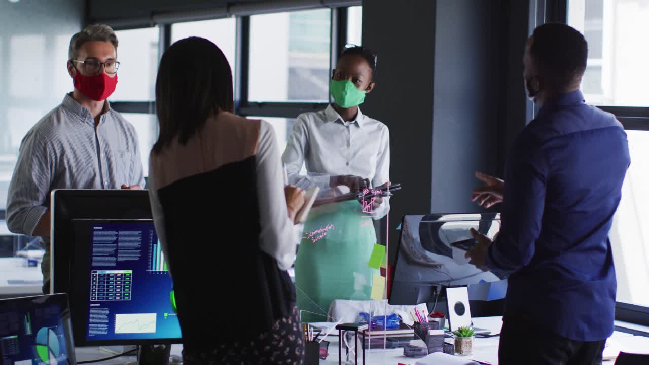 Office colleagues wearing face masks discussing with each other at modern office