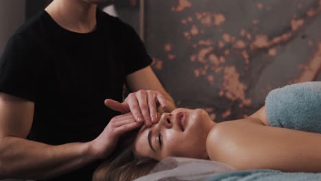 close-up of a gentle face massage of a young woman in a massage room with soft light