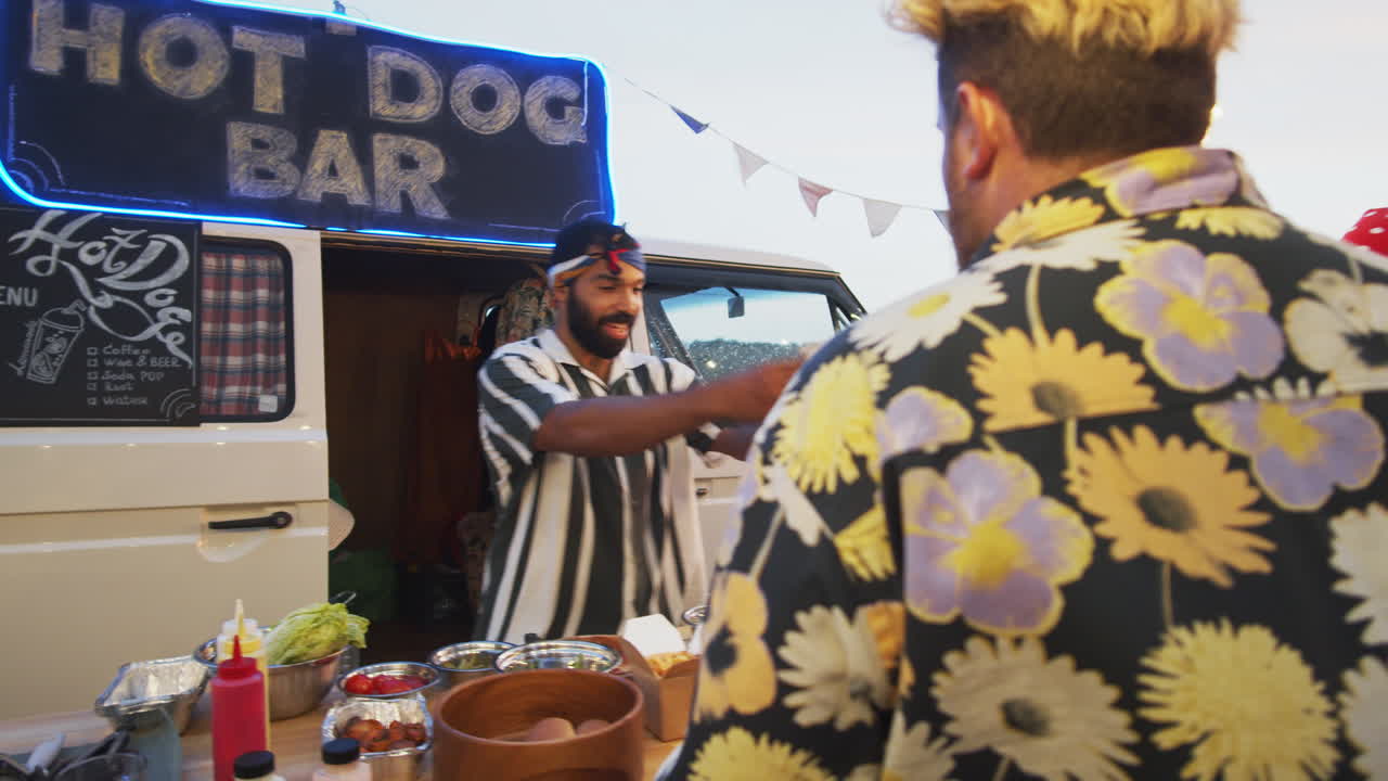 여름 축제 에서 음식 트럭 에서 핫도그 를 주문 하고 춤 을 추는 사람 들