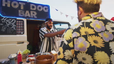 people dancing and ordering hot dogs at food truck on summer festival