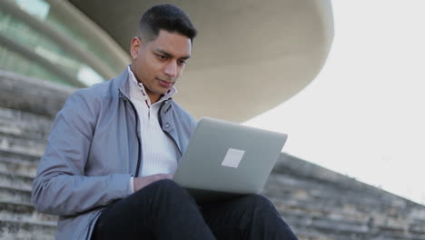 cheerful middle eastern businessman working with laptop outdoor